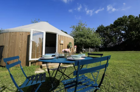 Udendørs spiseplads foran en glamping yurt på Camping La Ferme de Croas Men med grønt græs og blå himmel.