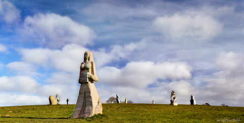 Sculture di pietra su un campo verde sotto un cielo azzurro al glamping Camping La Ferme de Croas Men.