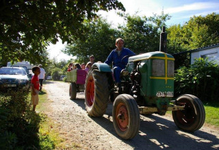 Gezinnen genieten van een rit met de tractorwagen op Camping La Ferme de Croas Men, omgeven door natuur.