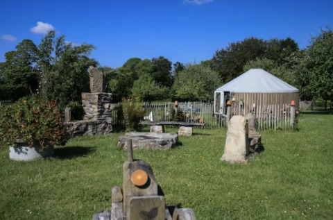 Glamping accommodation at Camping La Ferme de Croas Men featuring a yurt and stone features in a green field.