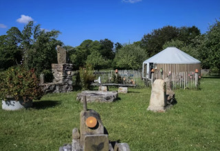 Glamping indkvartering på Camping La Ferme de Croas Men med yurt og steninstallationer i grønne omgivelser.