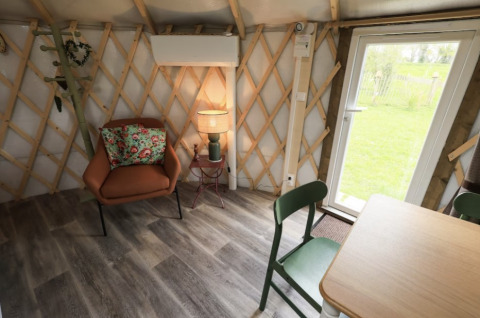 Gezellig interieur van glampingaccommodatie Camping La Ferme de Croas Men met stoel, tafel en lamp.