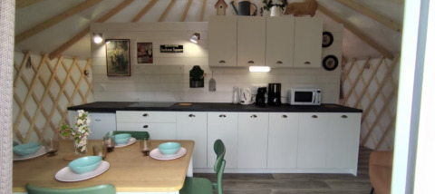 Cucina moderna e zona pranzo glamping al Camping La Ferme de Croas Men con stoviglie e decorazioni in legno.