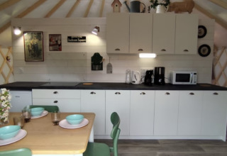 Moderne glamping keuken en eetruimte bij Camping La Ferme de Croas Men met servies en houten decoratie.