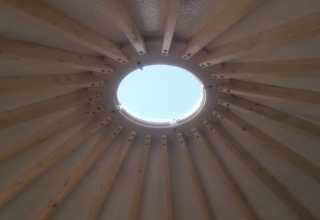 Vigas de madera y tragaluz en el techo de una yurta glamping en Camping La Ferme de Croas Men, Bretaña.