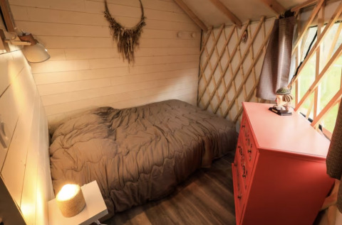 Gemütliches Zimmer mit Bett, grauer Decke, roter Kommode und Fenster auf Camping La Ferme de Croas Men.