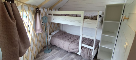 Innenansicht einer gemütlichen Glamping-Unterkunft mit Etagenbett, Regalen und Holzdekor auf Camping La Ferme de Croas Men.