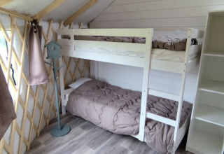 Cozy glamping room interior at Camping La Ferme de Croas Men featuring bunk beds, shelving, and rustic decor.