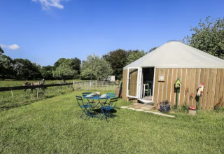 Außenaufnahme von Glamping-Unterkunft auf Camping La Ferme de Croas Men mit Rundhütte und Gartenmöbeln.