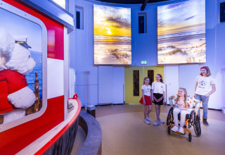 Kinderen spelen binnen bij Bio Vakantieoord - Glampingtenten Veluwe met berenexpositie en strandfoto's.