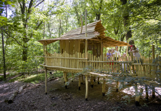 Children play on a wooden treehouse in the forest at Bio Vakantieoord - Glampingtenten Veluwe glamping site.