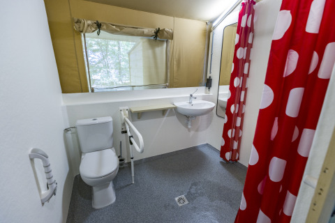 Accessible bathroom in glamping tent at Bio Vakantieoord Glampingtenten Veluwe with red polka dot shower curtain.