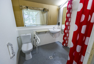 Accessible bathroom in glamping tent at Bio Vakantieoord Glampingtenten Veluwe with red polka dot shower curtain.