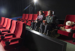 Dos niños en silla de ruedas ven una película en el cine de Bio Vakantieoord - Glampingtenten Veluwe.