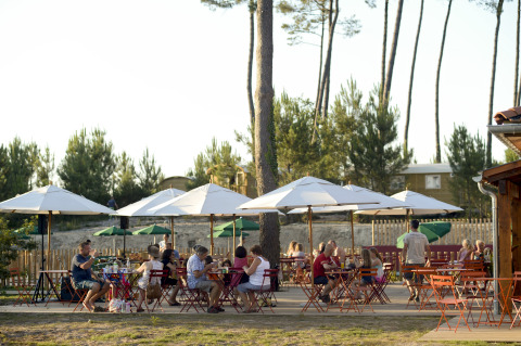 Zona pranzo all'aperto con ombrelloni e ospiti da Huttopia Landes Sud - Glamping Aquitaine in Francia.