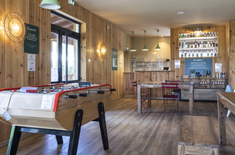 Sala común en Huttopia Landes Sud Glamping Aquitaine con futbolín y decoración de madera natural.