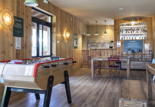 Indendørs fællesområde på Huttopia Landes Sud Glamping Aquitaine med bordfodbold og bar.