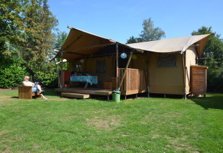 Luxe lodgetent op vakantiepark De Kleine Belties in Nederland, met gasten die genieten van de buitenruimte.