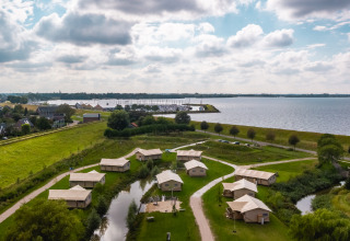 Luchtfoto van safarilodges bij Vakantiepark IJsselhof in Noord-Holland, gelegen aan een meer met groen.