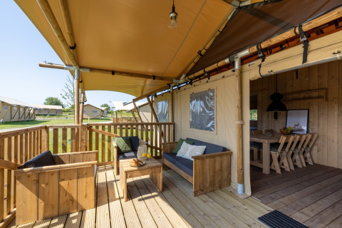 Outdoor glamping terrace with wooden furniture at Vakantiepark IJsselhof - Safarilodges Noord-Holland.