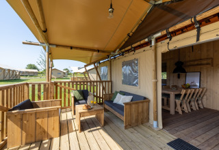 Terraza exterior con muebles de madera en una glamping en Vakantiepark IJsselhof - Safarilodges Noord-Holland.