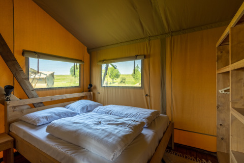 Innenansicht einer Safarilodge im Vakantiepark IJsselhof Noord-Holland mit komfortablem Bett und Aussicht.