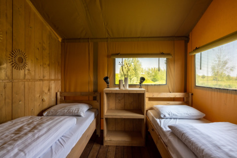 Interieur van een glamping safarilodge op Vakantiepark IJsselhof met twee bedden en uitzicht buiten.
