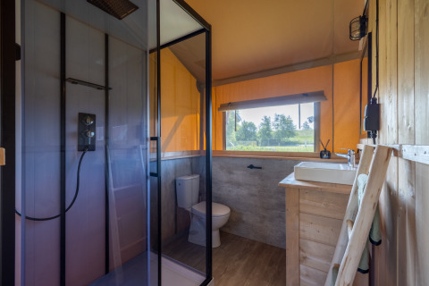 Bathroom of glamping accommodation at Vakantiepark IJsselhof Safarilodges Noord-Holland with outdoor view.