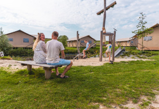 Familie nyder glamping på Vakantiepark IJsselhof Safarilodges i Noord-Holland med legeplads og telte.