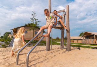 Kinderen spelen op een houten glijbaan in de speeltuin voor safarilodges op Vakantiepark IJsselhof in Holland.