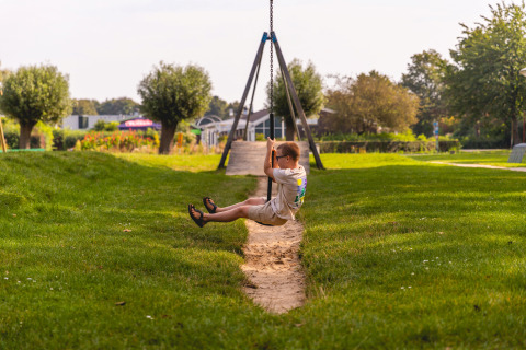 A child rides a zip line in the lush outdoors at Vakantiepark IJsselhof Safarilodges in North Holland.