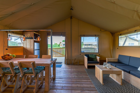Vue intérieure d’un hébergement glamping aux Safarilodges Vakantiepark IJsselhof avec sol en bois et mobilier confortable.