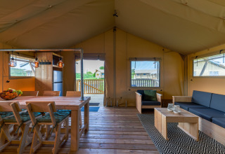 Innenansicht einer Glamping-Unterkunft bei Vakantiepark IJsselhof Safarilodges mit Holzboden und Sitzbereich.