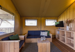 Interior de una tienda glamping Safarilodge en Vakantiepark IJsselhof, Holanda del Norte, con muebles de madera.