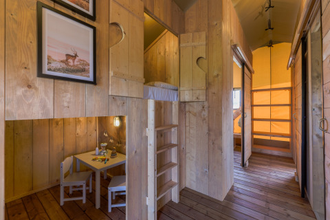 Innenansicht einer gemütlichen Glampinghütte mit Holzinterieur, Hochbett und Kindertisch bei IJsselhof.