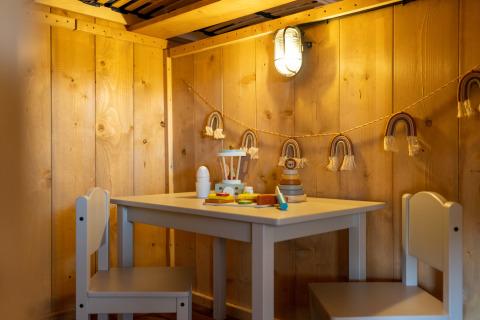 Knusse speelhoek voor kinderen met houten wanden, tafeltje, stoelen en speelgoed in Safarilodges Noord-Holland.