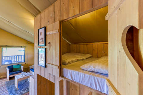 Indvendig udsigt af en komfortabel træhytte i Safarilodges på Vakantiepark IJsselhof med senge og opholdsområde.