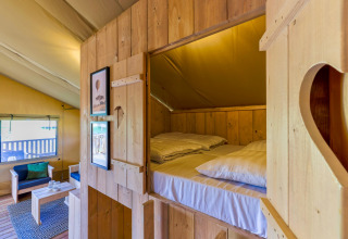 Indvendig udsigt af en komfortabel træhytte i Safarilodges på Vakantiepark IJsselhof med senge og opholdsområde.