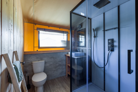 Salle de bain moderne dans une safarilodge du Vakantiepark IJsselhof, avec douche, WC et fenêtre.