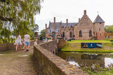 Famille traversant un pont vers un château près du site de glamping Vakantiepark IJsselhof - Safarilodges.