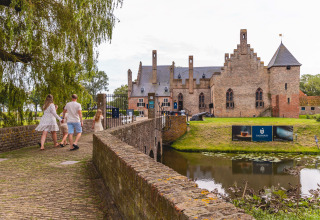 Gezin wandelt over een brug naar een kasteel nabij Vakantiepark IJsselhof - Safarilodges glamping Noord-Holland.