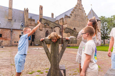 Children playing with a medieval pillory at the courtyard of Vakantiepark IJsselhof Safarilodges in North Holland.