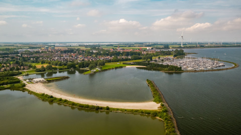 Vista aérea de la playa, marina y Vakantiepark IJsselhof - Safarilodges en glamping en Noord-Holland, Países Bajos.