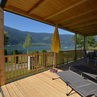 Wooden terrace overlooking lake and mountains at Terrassencamping Ossiacher See - Stacaravans Karinthië.