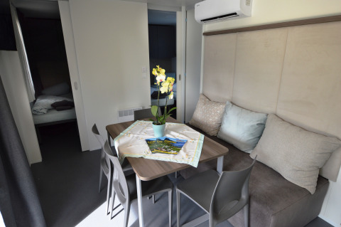 Interior de alojamiento glamping en Terrassencamping Ossiacher See con mesa, sillas, sofá y flores.