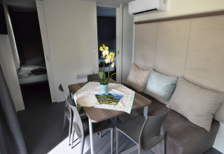 Interno di una sistemazione glamping a Terrassencamping Ossiacher See con tavolo, sedie, divano e pianta.