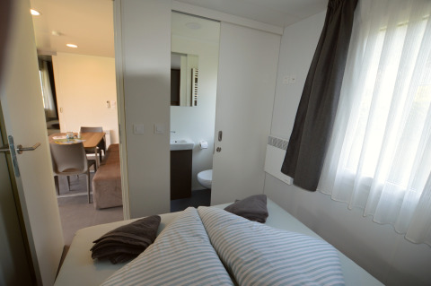 Slaapkamer, badkamer en eetruimte in een glamping accommodatie op Terrassencamping Ossiacher See.