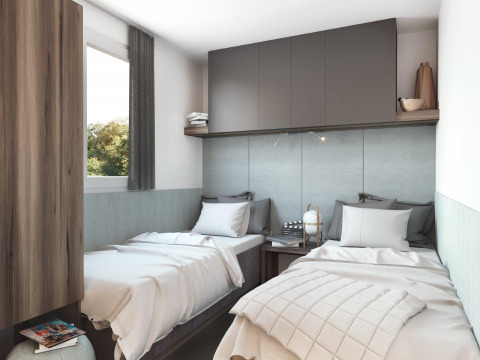 Alojamiento glamping moderno con dos camas individuales, armarios grises y decoración acogedora.