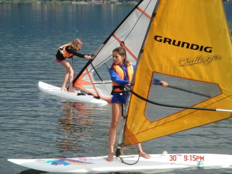 Deux enfants font de la planche à voile sur le lac au Terrassencamping Ossiacher See - Stacaravans Karinthië en Autriche.