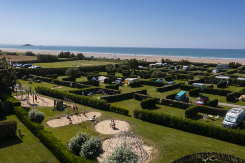Campingplatz am Strand mit Parzellen, Zelten, Wohnmobilen und Spielplatz, aus der Vogelperspektive.